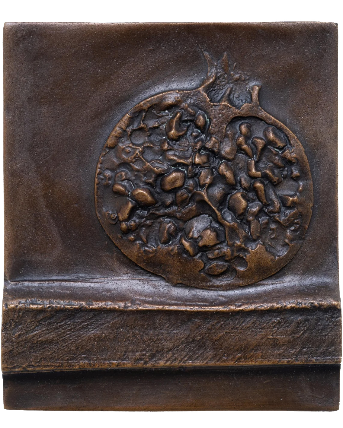 A Bronze Relief Sculpture Featuring A Textured, Detailed Pomegranate Cut In Half, Set Against A Square Background With A Horizontal Ridge Near The Bottom.