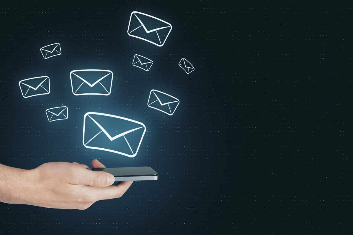 A Hand Holds A Smartphone With Illustrated Email Icons Floating Above It, Symbolizing Sending Or Receiving Digital Messages On A Dark Background.