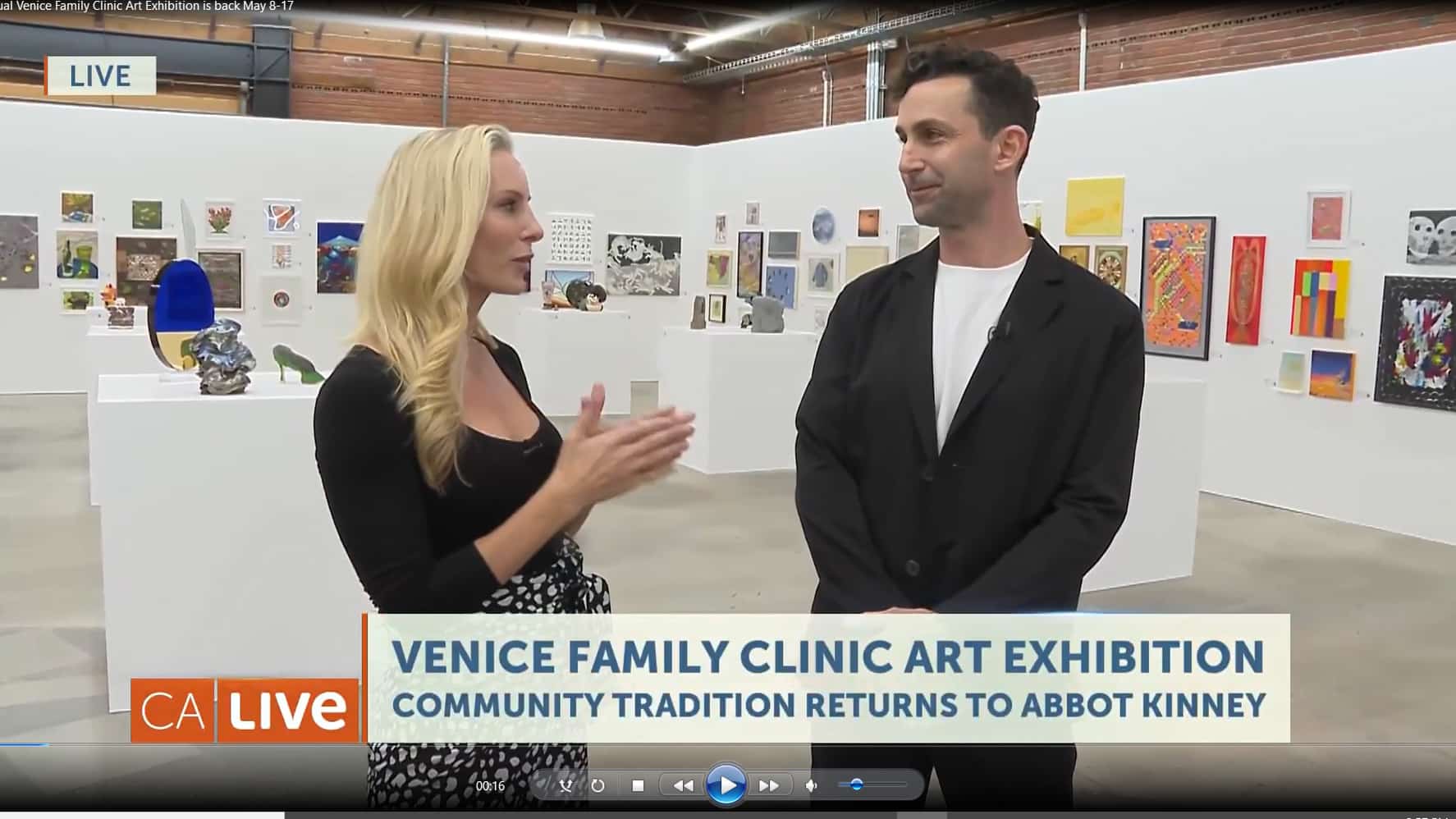 Two People Speak In An Art Gallery For A TV Segment. The Gallery Walls Behind Them Display Various Colorful Artworks. A Headline Reads: Venice Family Clinic Art Exhibition. Community Tradition Returns To Abbot Kinney. CA Live. Two People Speak In An Art Gallery For A TV Segment. The Gallery Walls Behind Them Display Various Colorful Artworks. A Headline Reads: Venice Family Clinic Art Exhibition. Community Tradition Returns To Abbot Kinney. CA Live.